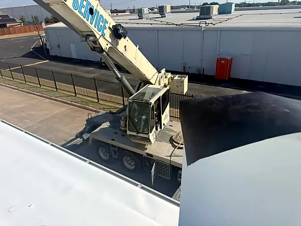 Crane lifting roofing materials onto a commercial building