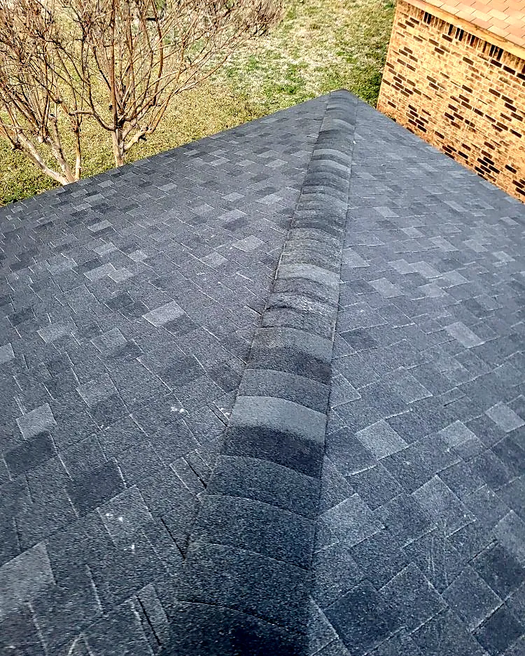 Ridge cap shingles finished neatly against a brick wall