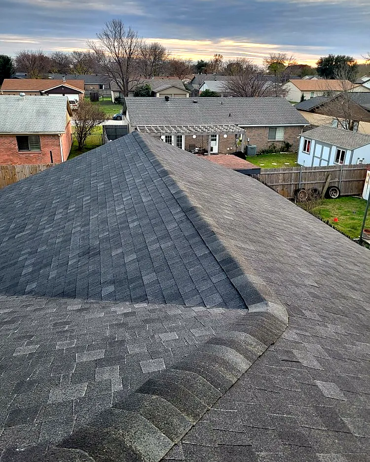 New architectural shingles and hip ridge cap at sunset over a Fort Worth neighborhood