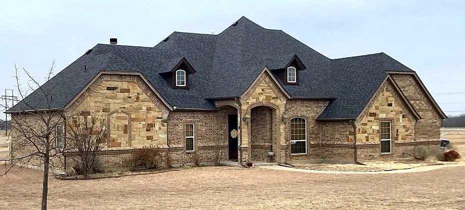 Stone ranch home in North Texas with a newly installed charcoal shingle roof