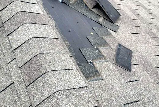 Wind-damaged and missing asphalt shingles on a roof